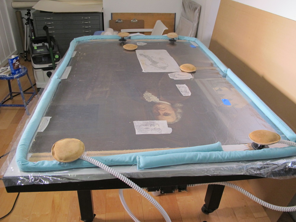  The painting was placed face up on a heat/suction table to reduce distortions/undulations of the canvas.&nbsp; The table applies even heat and pressure to allow the undulations to relax. 