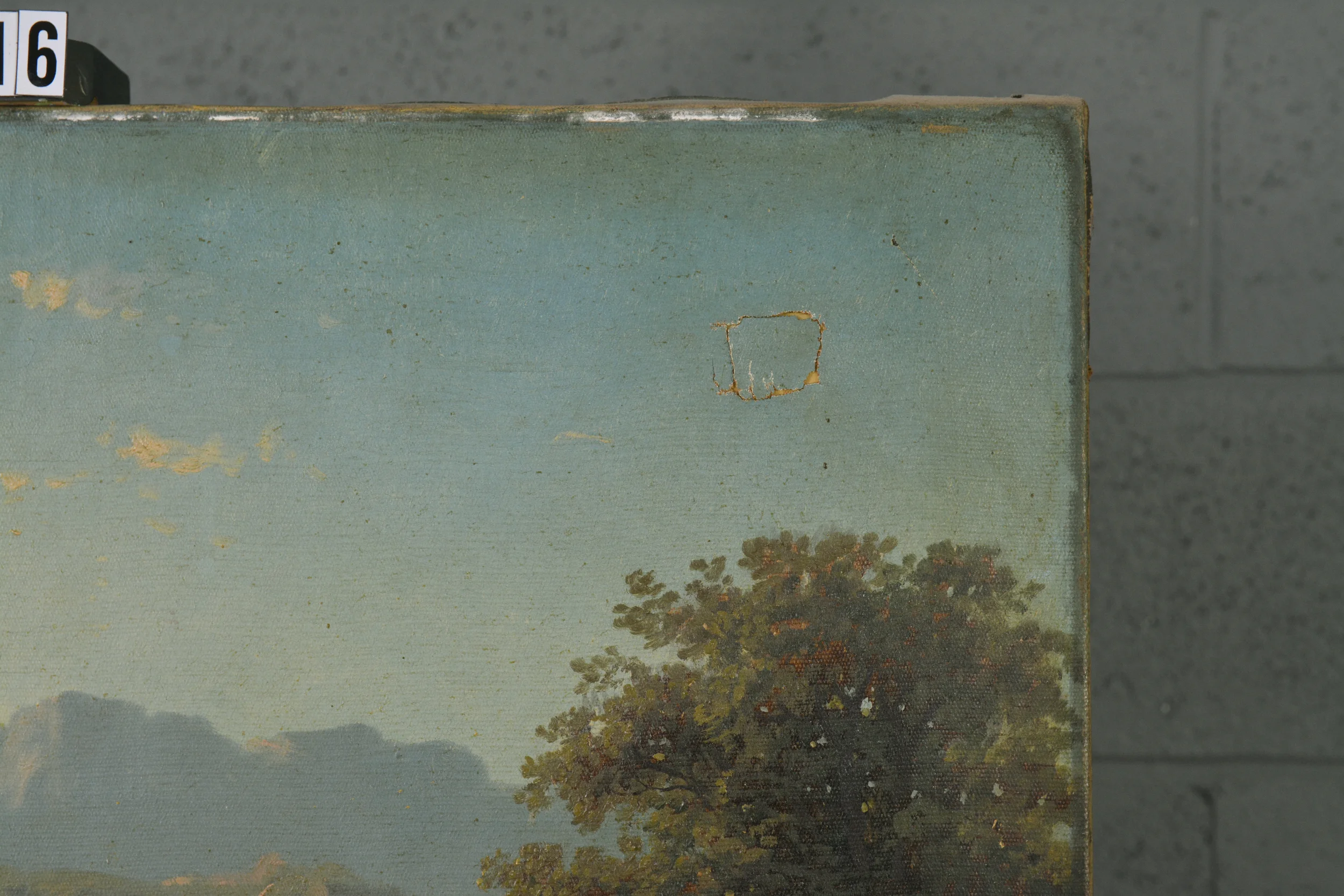 Before treatment photo of a landscape with a round tear in the upper right corner.