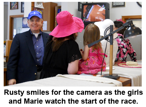 Southgate Coins owner Rusty Goe poses for the cameras as his coin shop employees view the horse race.