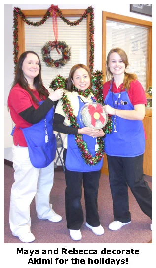 Maya and Rebecca decorate Akimi with holiday garland at Southgate Coins