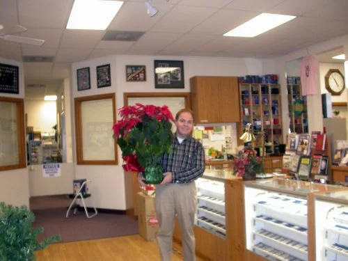 Southgate Coins owner Rusty Goe poses with poinsettias.