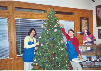 Southgate Coins owner Marie and employee Somer put up the Christmas tree