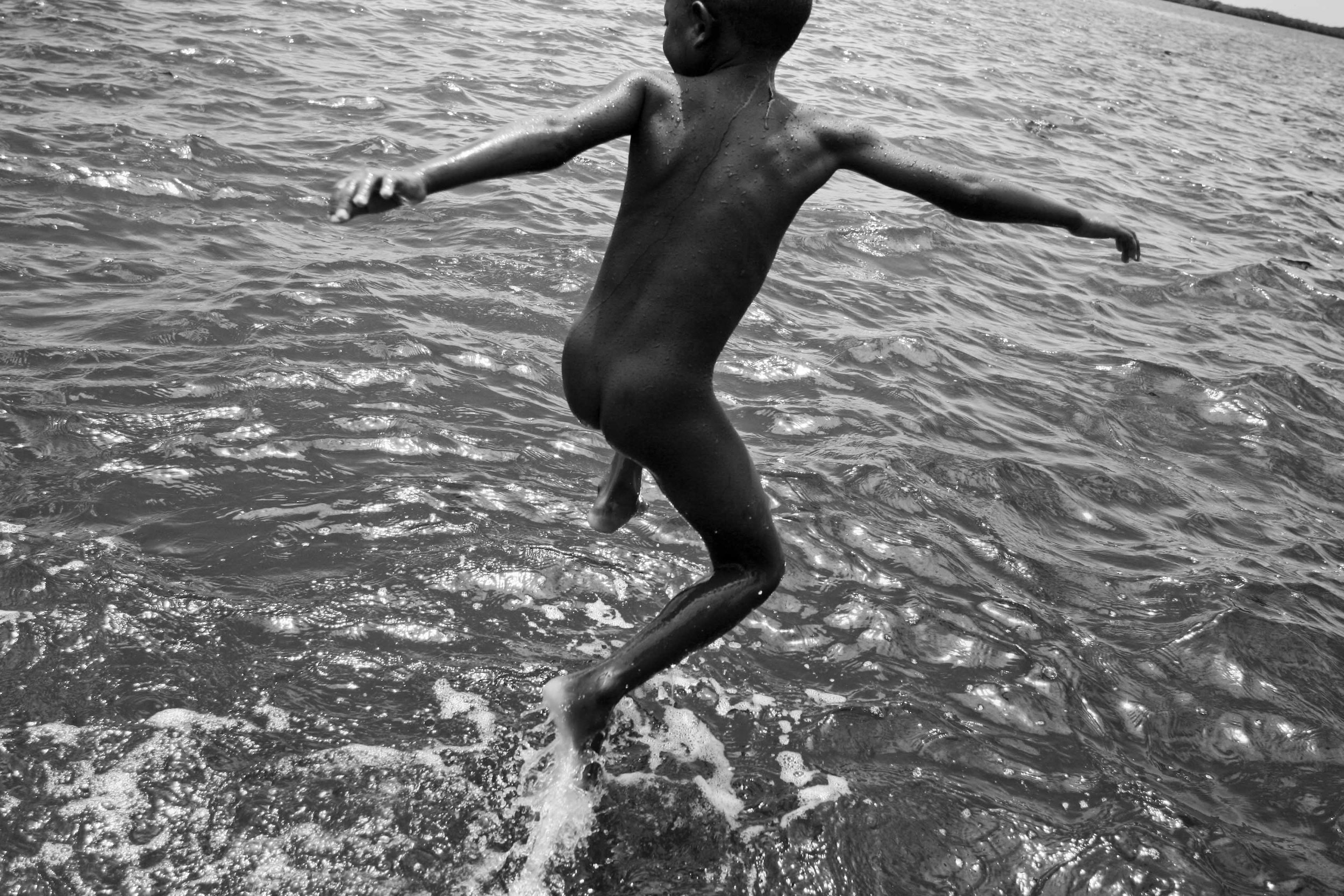  A child jumps into the water after a day of work picking shells. 2011. 