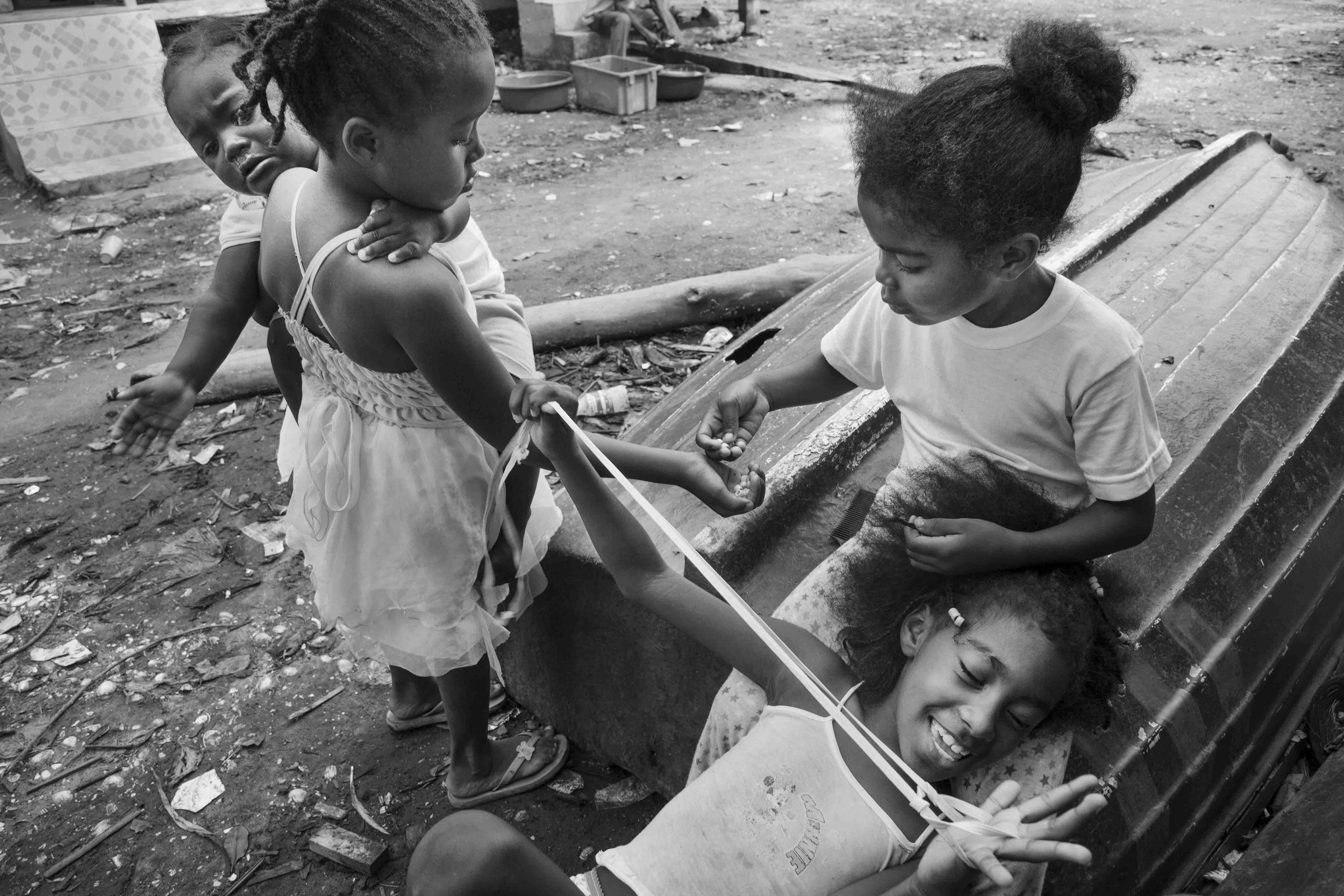  A group of girls play on top of a capsized boat on dry land. According to local health authorities, children make up to 70% of the population in the Mangrove Reserve. Tambillo, Ecuador. 2014 