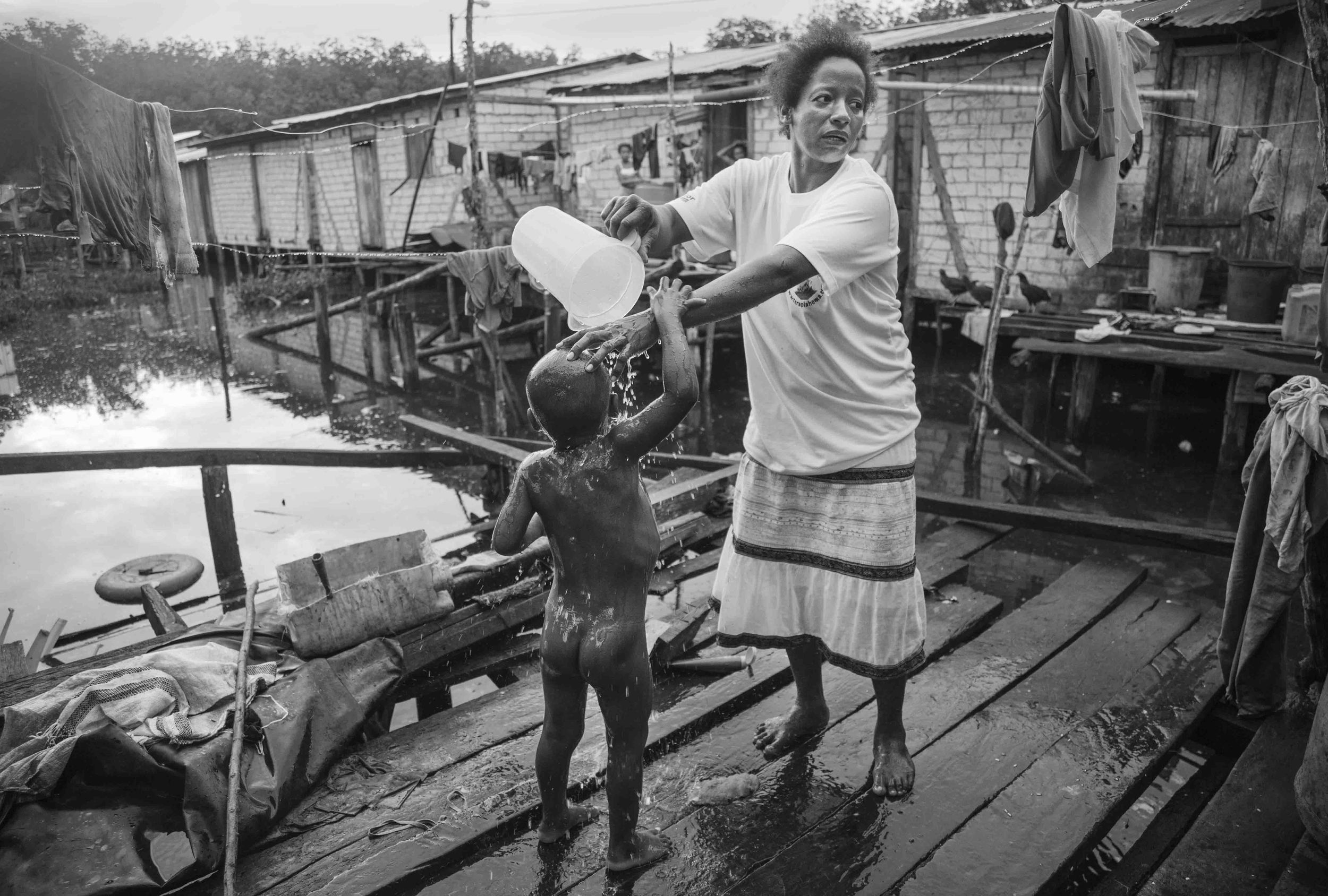  Rosa Quiñones bathes his son Efraín before sending him off to school. Rosa has 7 children, 2 of which pick shells to contribute to the family economy. Tambillo, Ecuador. 2010 