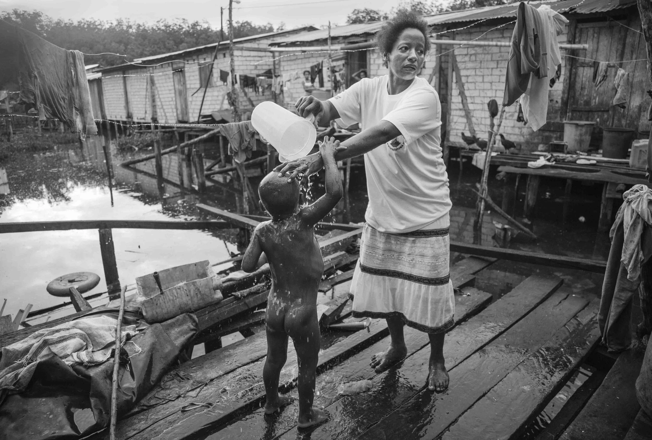 Rosa Quiñones bathes his son Efraín before sending him off to school. Rosa has 7 children, 2 of which pick shells to contribute to the family economy. Tambillo, Ecuador. 2010