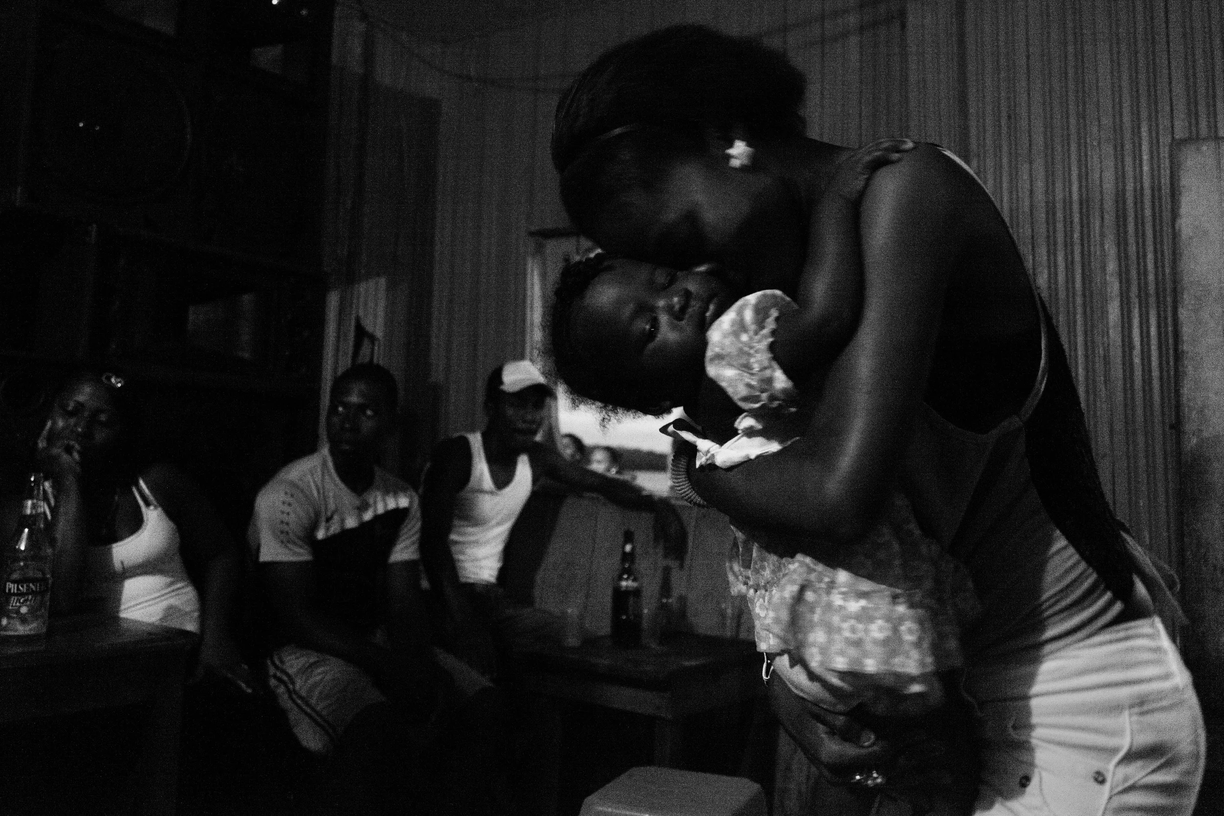 A woman dances with a baby at a bar in the community of Tambillo. In the communities, Sundays are mostly reserved for drinking and partying. Tambillo, Ecuador. 2014.