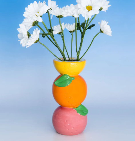 Cheerful stacked oranges decorative vase with a wide opening for flowers or kitchen utensils on a sunny countertop.