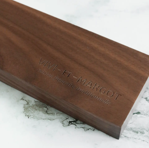 Close-up of the luxurious solid walnut magnetic knife block featuring the engraved Vivi et Margot logo, showcasing authentic French craftsmanship.