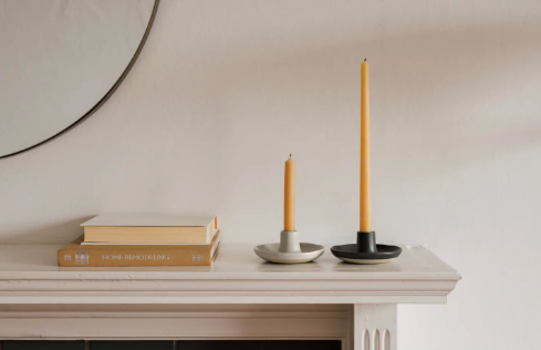An elegant stoneware candle holder with a speckled gray reactive glaze and organic shape, perfect for a modern home.