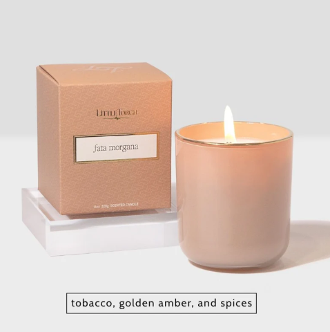 A warm, tan-colored candle and box from Little Torch named Fata Morgana, emitting a soft light to evoke the earthy and spicy essence of an ancient desert.
