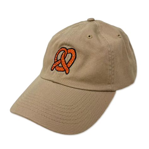 Side view close-up of the unstructured tan baseball cap featuring the unique pretzel embroidery.