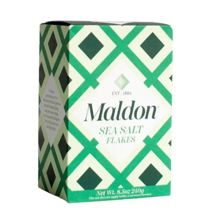 The iconic white and green box of Maldon Sea Salt Flakes, a premium hand-harvested finishing salt from England.