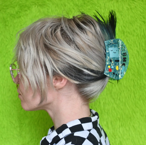 A blue-green hair claw shaped like the Bmo character worn by model.
