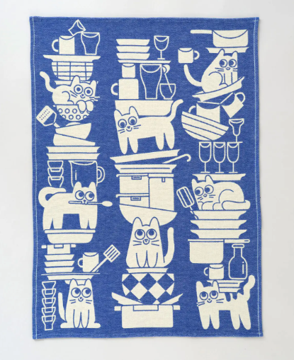 A humorous dish towel in a bold blue color featuring cartoon cats "helping" with the dishes.