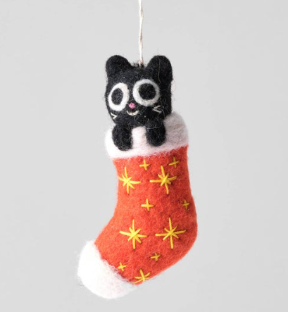 A black felted wool cat ornament peeking out of a red stocking embroidered with yellow stars.
