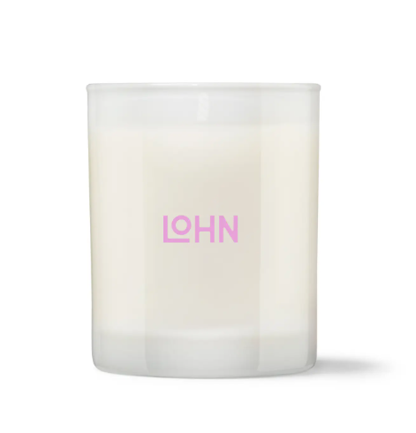 The LOHN Lato Lemon & Tonka Bean Candle, displayed in its elegant glass vessel with a matching lid and its beautifully designed box featuring a vibrant orange and pink motif.