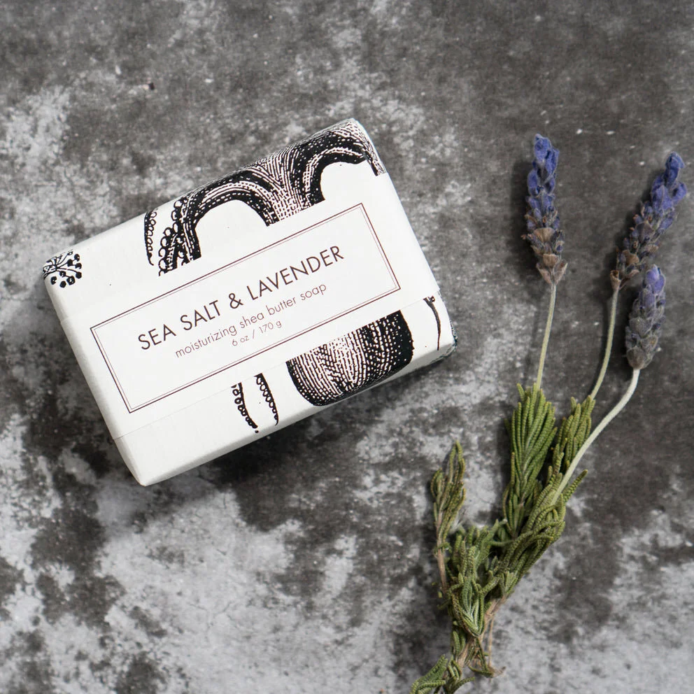 A bar of Sea Salt & Lavender shea butter soap with lavender flowers and sea salt.