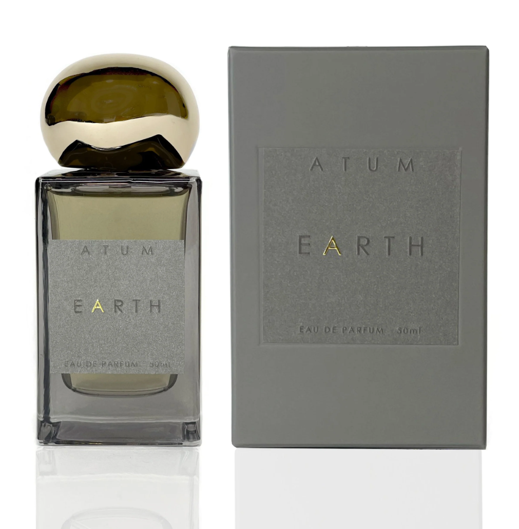 Earth Parfum by ATUM: The elegant tinted grey glass bottle with a gold cap, presented alongside its refined matte grey tray and carton packaging.