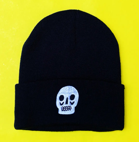 The edgy Skull Beanie by Kristina Micotti, a black knit hat with unique white skull embroidery on the cuff.