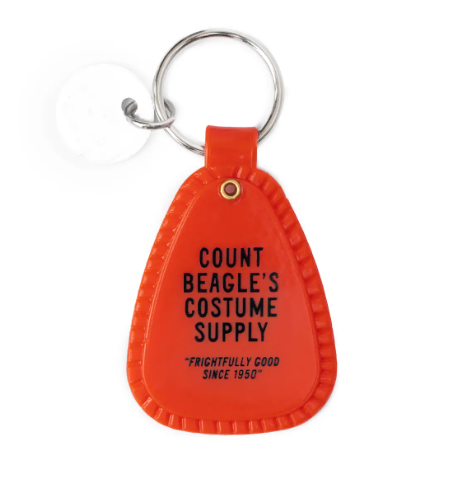 View the reverse side of the red Snoopy Dracula Saddle Keychain by Three Potato Four, featuring custom text highlighting Count Beagle's costume supply.