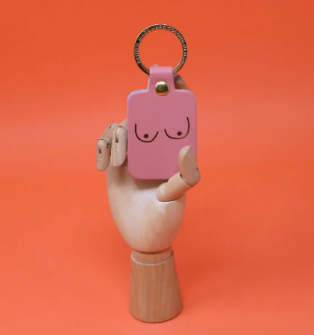 A unique and empowering pale pink leather keyring shaped like a boob, a playful symbol of strength and femininity.