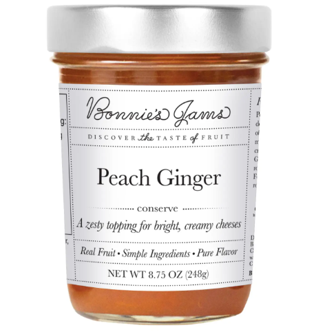 A glass jar of Bonnie's Jams Peach Ginger Jam with a white label, showing the vibrant color of the fruit conserve.