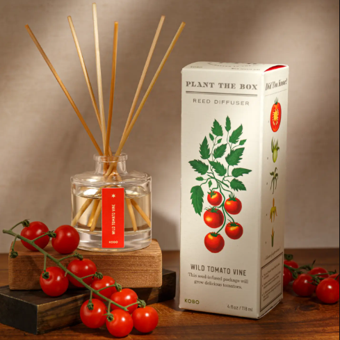 Style your home with the Wild Tomato Vine Diffuser by KOBO, displayed alongside fresh vine tomatoes and its plantable packaging on a rustic wooden table.