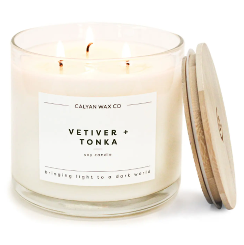 Create an inviting atmosphere with the Vetiver + Tonka 3-wick soy candle by Calyan Wax Co., featuring a clear glass tumbler and wooden lid.