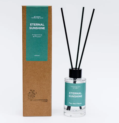 Infuse your space with vibrant energy using the Eternal Sunshine Fragrance Diffuser by Feu des Fleurs, featuring black reeds and a stylish teal label.