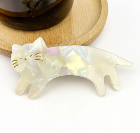 A glossy white acetate hair clip in the shape of a cat, featuring a sleek and minimalist animal-themed design.