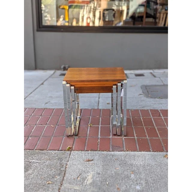 Vintage nesting tables stacked together outside a storefront, largest rosewood top and chrome frame