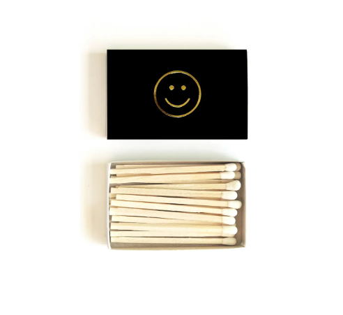 The Smiley Face Matchbox, featuring a simple gold embossed smiley face on a black background.