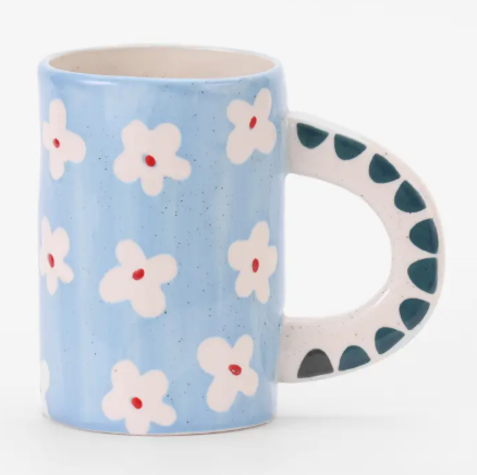 A hand-painted blue floral ceramic mug by ChagoArt featuring a soft blue background and a bold, patterned handle.