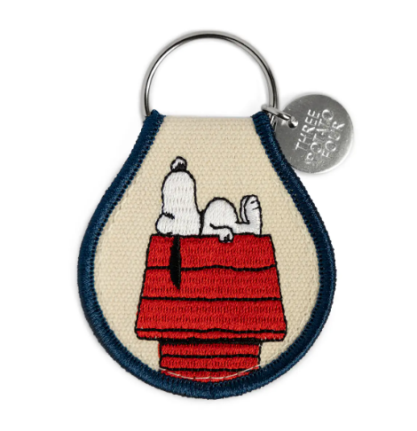 Double-sided Snoopy Doghouse patch keychain made from natural oxford cotton with a sturdy metal keyring.