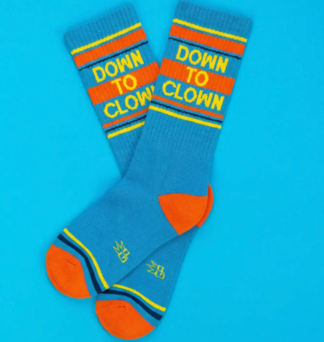 Close up of retro-style athletic socks featuring an orange contrast toe and heel with a bold block-letter "DOWN TO CLOWN" statement.