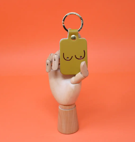 A unique and empowering ochre leather keyring shaped like a boob, a playful symbol of strength and femininity.