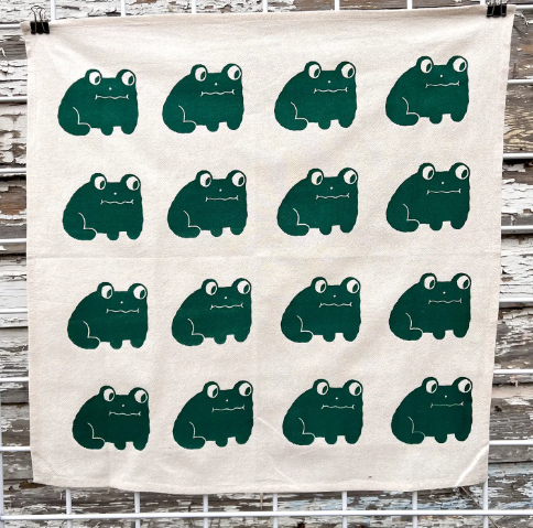 A lovely and fun hand-printed cotton tea towel with a bold frog design, ideal for a modern kitchen.