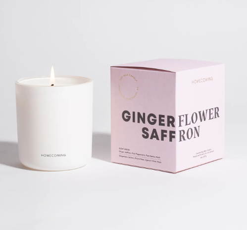 Watch the warm glow of the Homecoming Ginger Flower Saffron Soy Wax Candle as its flame casts a soft light, illuminating a cozy and inviting atmosphere.