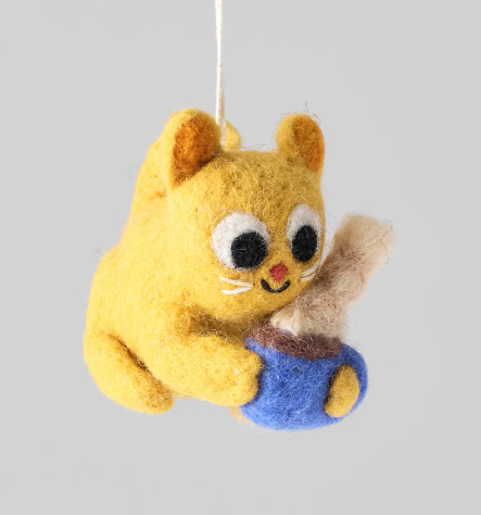A felted wool Chino, Cat and Mug Hanging Ornament featuring a yellow cat hugging a blue mug with steam coming out.
