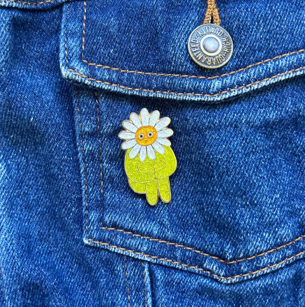 Close-up of the Flower Boy Enamel Pin, highlighting the glittery details and the intricate design of the Flower Boy.