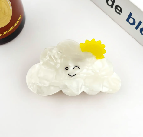 A close-up of the Sun style Cute Cartoon Cloud Hair Clip by TheDivaSoap featuring a winking face and a bright yellow sun accent.