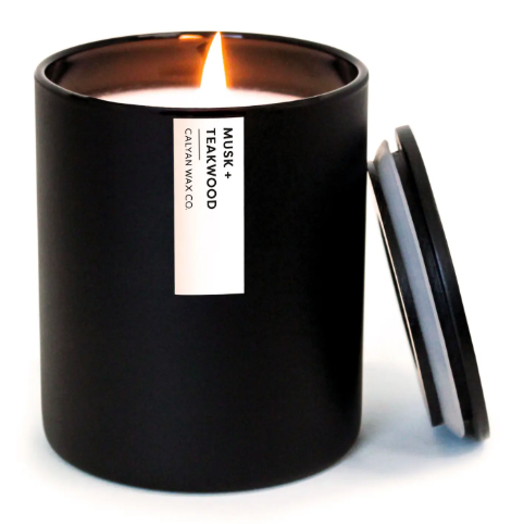 The sleek Musk + Teakwood candle with a modern matte black tumbler and matching wooden lid, a sophisticated accessory for any space.