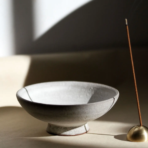 Close-up of the Ume Incense Chalice in Terracotta with an incense stick burning in a gold dome holder.