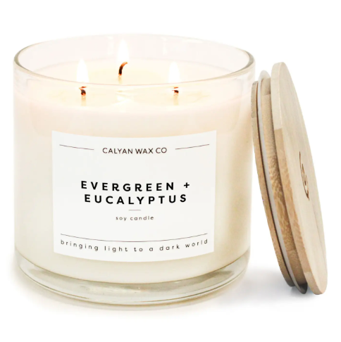 Create a serene home environment with the Evergreen + Eucalyptus 3-wick soy candle by Calyan Wax Co. in a clear glass tumbler with a wooden lid.