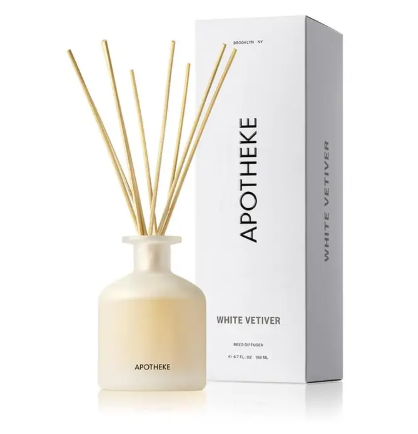 APOTHEKE White Vetiver Reed Diffuser set displaying a frosted translucent glass bottle filled with fragrance oil alongside a bundle of natural rattan reeds.