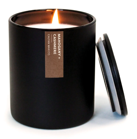 The sleek Mahogany + Cashmere candle with a modern matte black tumbler and matching wooden lid, a sophisticated accessory for any space.