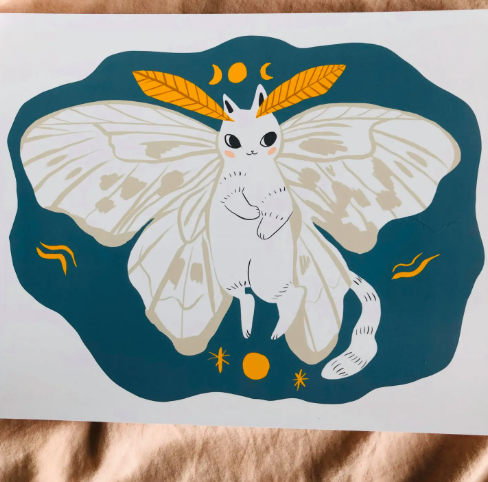 A lovely art print featuring the Poodle Moth Cat with white wings against a blue background, ready to bring charm and whimsy to your home decor.