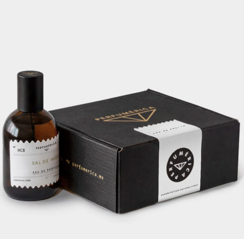 A close-up of the Sal De Mar Eau de Parfum bottle, showcasing the minimalist apothecary label and amber glass design.