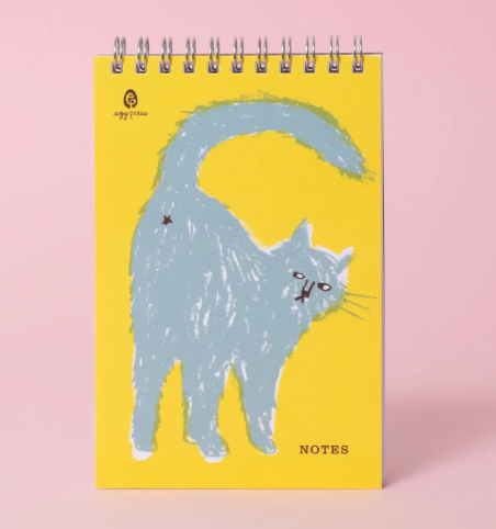 Brighten your desk with the Cat Butt Notes Spiral Notebook by Egg Press Manufacturing, featuring a playful blue cat illustration on a yellow cover.